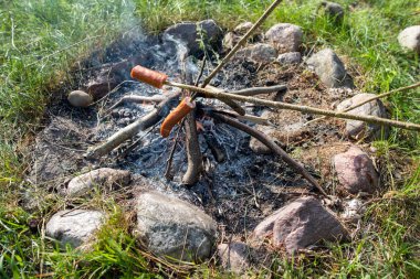Açık ateşte yağ damlayan lezzetli sosisler. Bir firepl