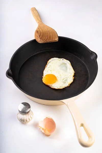 Lekker gebakken ei op een gietijzeren pan. Bereiden van een smakelijk ontbijt. — Stockfoto