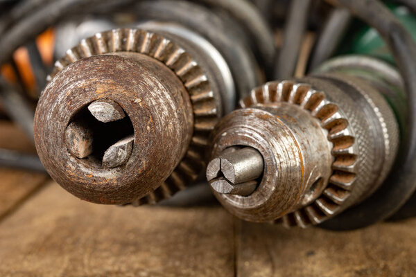 Old drills on a wooden workshop table. Rusty drill holder in an 