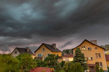Czluchow, Pomeranian Voivodeship / Polonya - 15 Haziran 2019: Fırtına sırasında tek ailelik evlerin üzerinde karanlık fırtına bulutları. Fırtına uzun pozlama da fotoğraflandı. Yaz mevsimi.