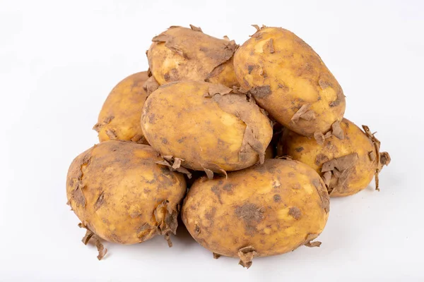 Jonge aardappelen op een witte keukentafel. Groenten en moeskruiden — Stockfoto