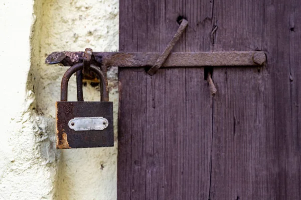 Der alte Mann wischt von einem Vorhängeschloss in der Tür des Hofgebäudes — Stockfoto