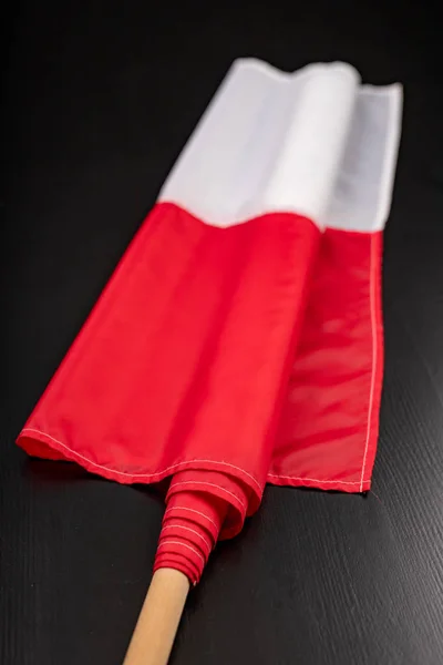 Polish flag on a dark table. A flag attached to a wooden spar. — Stock Photo, Image