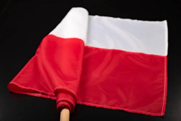 Польский флаг на тёмном столе. Флаг, прикрепленный к деревянному шпату . — стоковое фото