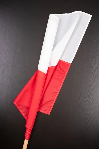 Polská vlajka na tmavém stole. Vlajka připojená k dřevěnému Spar. — Stock fotografie