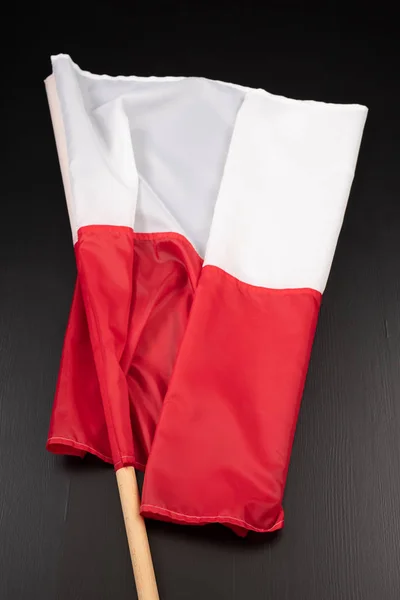 Polish flag on a dark table. A flag attached to a wooden spar. — Stock Photo, Image