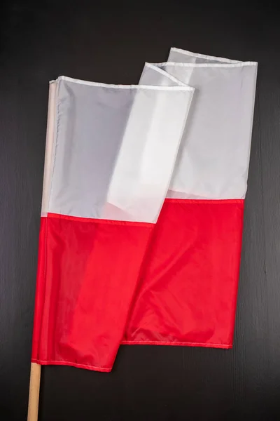 Polish flag on a dark table. A flag attached to a wooden spar. — Stock Photo, Image