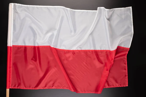 Polish flag on a dark table. A flag attached to a wooden spar. — Stock Photo, Image