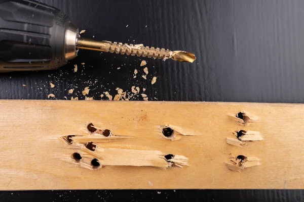 Drilling in a piece of dry planed wood. Holes made in the worksh