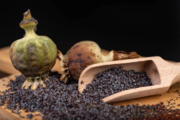 Fresh poppy seeds poured on a wooden kitchen board. Different po