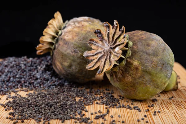 Fresh poppy seeds poured on a wooden kitchen board. Different po