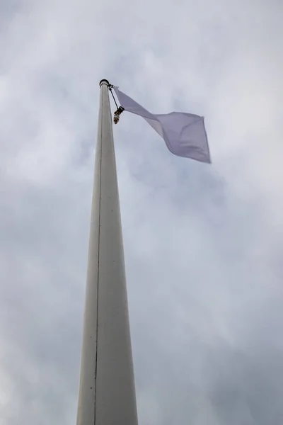 White flag on the mast near the beach. Flag on a background of c — Stock Photo, Image