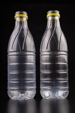 Yiyecek içecekten sonra plastik şişe. Koyu bir masa üzerinde tek kullanımlık ambalaj. Siyah arka plan.