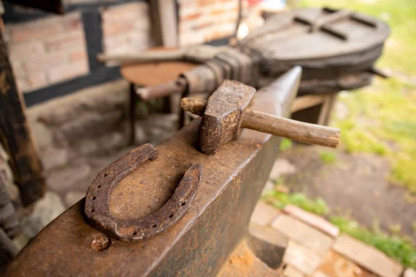 Hulpmiddelen in een oude smederij. Hoefijzer en hamer op een — Stockfoto