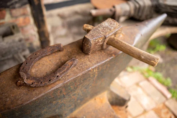 Tools in an old blacksmith's workshop. Horseshoe and hammer on a — Stock Photo, Image