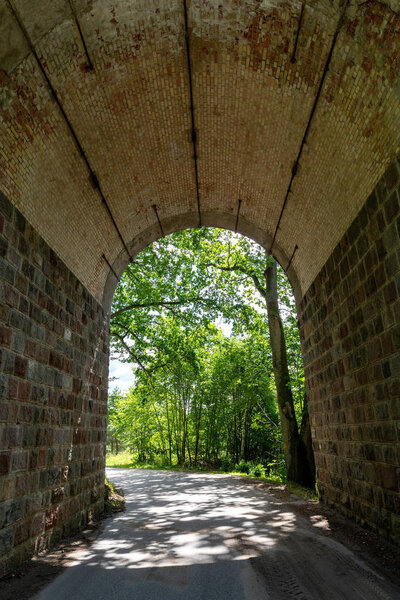 Asphalt road leading through a stone tunnel. A short tunnel in a