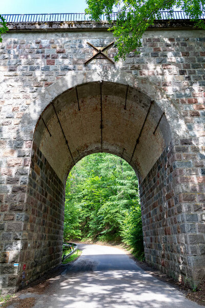 An old stone bridge over a small river. Railway crossing across 