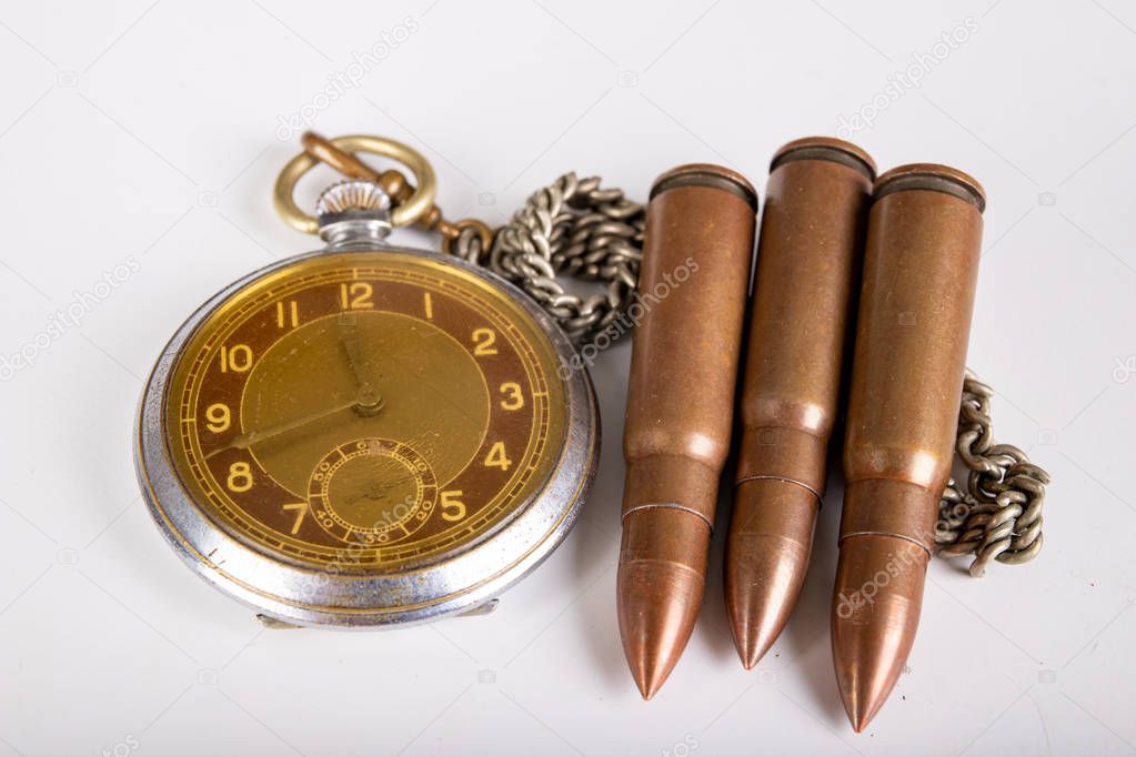 Old clock and ammunition on a white table. Explosive material an
