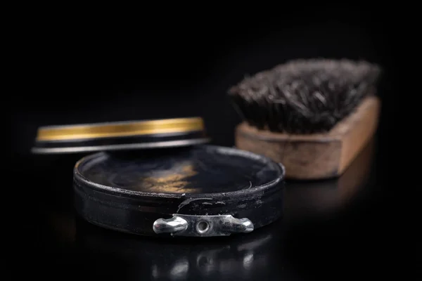 Black shoe polish, brush and shoes on the table. Accessories for