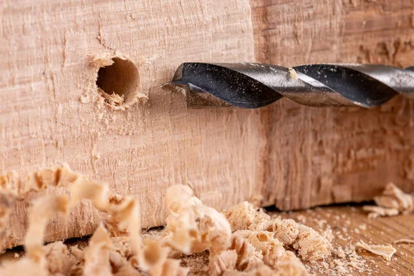 Drilling holes in raw wood. Carpentry drill in a carpentry works