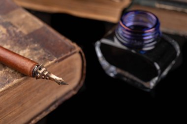 Karanlık bir masaya mürekkeple yazmak için eski bir ucu. Antik calligrap