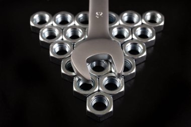 Nikel kaplama somunlar ve anahtarlar bir atölye masasında. Araçlar bir 