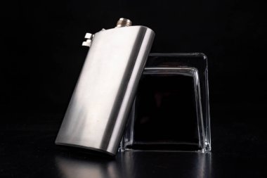 Metal shaker, kalça şişesi ve ters votka bardağı. Barmen acce