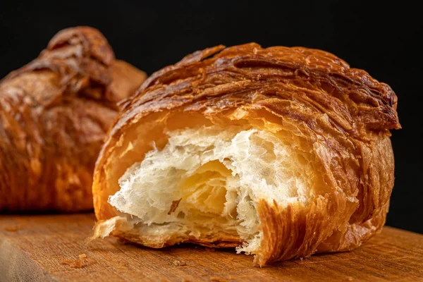 Croissant fresco saboroso em um quadro de pão escuro . — Fotografia de Stock