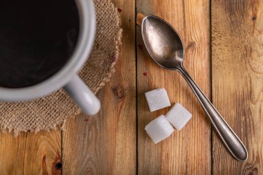 Gri kupada siyah kahve ve tahta bir masada bir çay kaşığı.