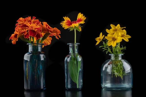 Fresh wild flowers in a glass vase on a dark table. Beautiful co