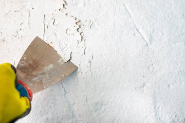 Metal bir spatulayla duvardaki eski boyayı çıkarıyorum. Küçük pai