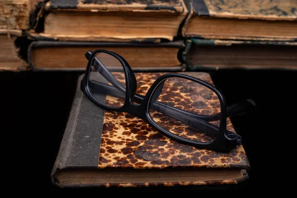 Old yellowed book and black glasses.