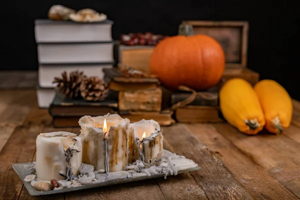 Livros velhos, abóbora e velas em uma mesa de madeira . — Fotografia de Stock