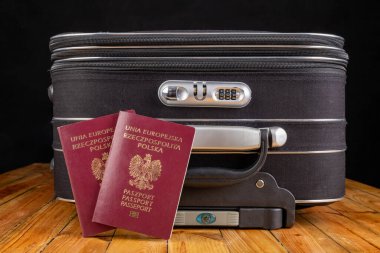 Büyük bir seyahat çantası ve Polonya pasaportu. Yurtdışına gitmek için hazırlanmış bavullar. Koyu arkaplan.