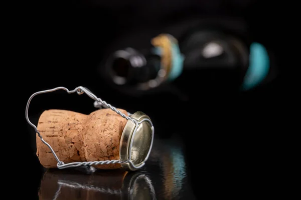 Champagne cork on a dark table. Metal basket and bottle stopper with alcoholic liquor. Black background.