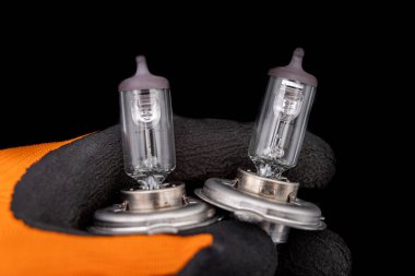 Bir adamın eldivenli elinde patlamış ampuller. Farlar için değiştirilebilir araba aksesuarları. Koyu arkaplan.