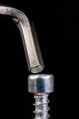 Allen karanlık bir masada vida ve anahtar kullanıyor. Evde mobilya montajı için aksesuarlar. Siyah arkaplan.