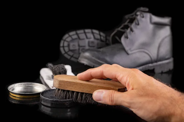 Polishing and cleaning leather shoes with a brush. Cleaning work shoes. Dark background.