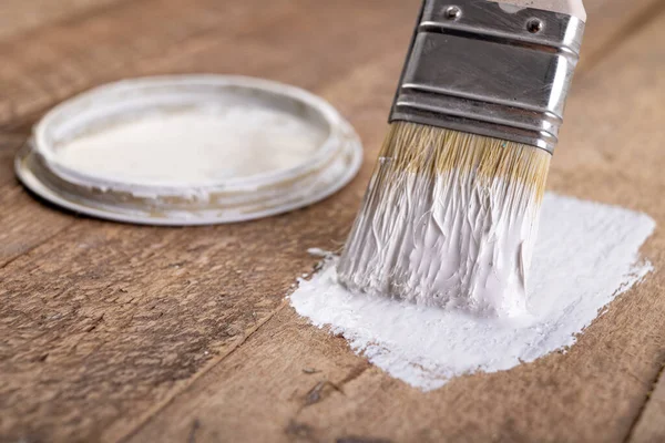 Painting raw wood with white paint. Minor painting work at home. Light background.