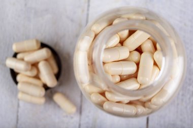 Plastik bir kapta tıbbi pastiller. Pastillerde hazırlanmış tüketim ilaçları. Hafif arkaplan.