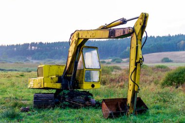 Çayırda duran harap olmuş bir siper kazıcısı. Hatalı inşaat aksesuarları. Sonbahar mevsimi.