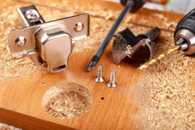 Çipin içinde yumuşak bir kapağı olan metal menteşelerin yerleştirilmesi. Mobilya montajında küçük marangozluk işleri. Atölye - Atölye.