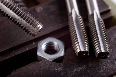 Mengenedeki metal bir cevize iplik geçirmek. Küçük bir çilingir atölyede çalışıyor. Hafif arkaplan.