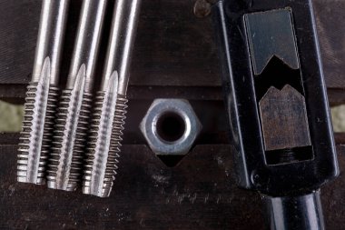 Mengenedeki metal bir cevize iplik geçirmek. Küçük bir çilingir atölyede çalışıyor. Hafif arkaplan.