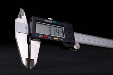 Karanlık bir masada elektronik kalibre. Ekranda gösterilen ölçülmüş değerin ölçümü. Koyu arkaplan.