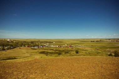 Yazın Steppe. Açık mavi gökyüzünün arka planında yeşil çimenler ve kır çiçekleriyle kaplı kumlu bozkır tepelerinin güzel bir alt manzarası. Arkaim rezervi.