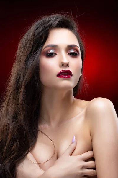 美しい魅力的なブルネットの少女の肖像画は肉感的 彼女の手で彼女の裸胸をカバーしています 赤い唇にきらめく 健康的な滑らかな肌 黒と赤の背景 コピー スペース — ストック写真