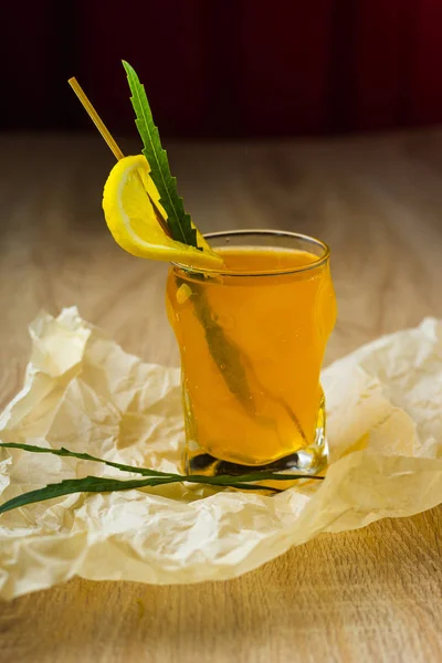 레몬과 커튼의 배경에 테이블에 구겨진된 포장지에 조각으로 노란색 주스의 유리를 — 스톡 사진