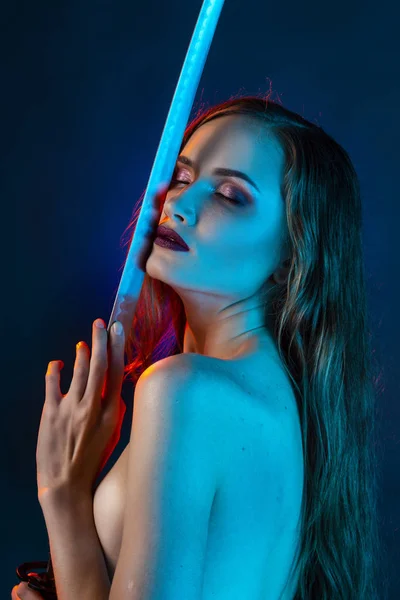 여자는 그녀의 Katana 빨간색과 파란색 불빛에 파란색 배경에 그것으로 가슴을 — 스톡 사진