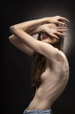 Güzel ince esnek atletik üstsüz kız modeli ile saçları gri siyah degrade arka plan üzerinde çıplak onun meme kapsar. Sağlıklı cilt. Uzay kopyalayın. Reklam, ticaret ve kavramsal tasarım.